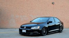 a black car parked in front of a brick wall