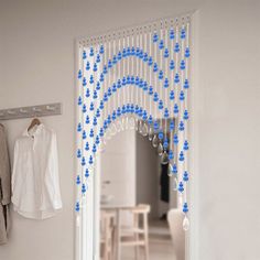 a white door with blue beads hanging from it's side and a mirror on the wall