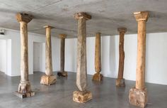 several wooden pillars in an empty room with concrete floors