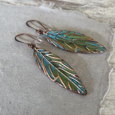 These hand painted artsy copper leaf earrings are a unique and striking accessory that have been crafted in our island studio using a special house patina paint blend resulting in a beautiful blue green finish reminiscent of the Caribbean sea. Once the patina process is complete, we buff and seal the copper for durability and to prevent tarnishing. Each pair of earrings are one-of-a-kind, with variations in the patina that add to their handmade charm. Size: 2.50 Inches from Lobe Ear Wire: Choice Hand Painted Copper Bohemian Earrings, Bohemian Hand Painted Copper Earrings, Artistic Hand Painted Copper Earrings, Artsy Hand Painted Copper Jewelry, Hand Painted Copper Artsy Earrings, Hand Painted Artsy Copper Earrings, Artsy Hand Painted Copper Earrings, Green Hand Painted Copper Earrings, Hand Painted Green Copper Jewelry