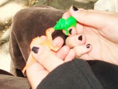 a person holding a small toy animal in their hands with other hand on the ground