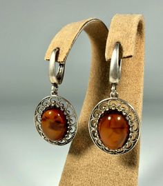 Elevate your style with our Handmade Earrings featuring spectacular orange amber set in textured 925 sterling silver. These exquisite earrings are designed for women who appreciate unique and original jewelry. The vibrant orange amber stones are beautifully complemented by the textured silver, creating a stunning and eye-catching piece that adds a touch of elegance and sophistication to any outfit. Product Details: Material: 925 Sterling Silver Stone: Orange Design: Textured Silver with Unique S Elegant Brown Jewelry With Polished Finish, Elegant Brown Polished Jewelry, Brown Handmade Jewelry For Formal Occasions, Handmade Brown Jewelry For Formal Occasions, Vintage Amber Dangle Earrings, Orange Round Sterling Silver Earrings, Elegant Brown Earrings For Anniversary, Classic Amber Sterling Silver Earrings, Elegant Amber Sterling Silver Earrings