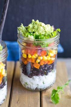 two mason jars filled with different types of food and garnished with cilantro