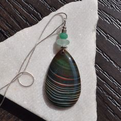 "Please enjoy browsing the many stone pendant varieties we have available.  This is a one of a kind, striking large waterdrop shaped pendant - Striped Onyx Agate, accented by a faceted aventurine gemstone bead and seafoam green genuine sea glass.  You'll fall in love with this exotic stone.  The hand wrapped bail is stainless steel wire for strength and a solid sterling silver slippy chain is included - your choice of length.  The main piece is 51x31x7mm.  Since this is such a variable pendant, Broken Bottle, Rock Necklace, Sea Sand, Agate Necklace, Glass Pieces, Stainless Steel Wire, Hand Wrap, Agate Pendant, Seafoam Green