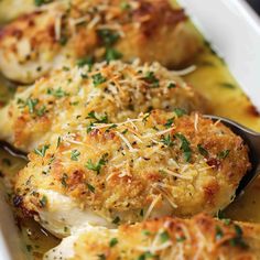 a close up of some food on a spoon in a casserole dish with cheese and parmesan sprinkles