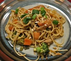 a plate with noodles, broccoli and carrots on it