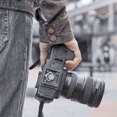 a person holding a camera in their hand with the lens attached to it's body