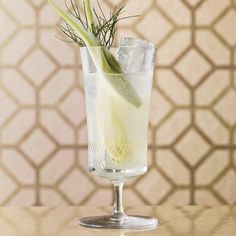 a tall glass filled with ice, lemon and some green garnish on the rim