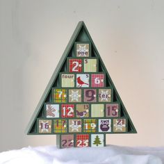 a christmas tree made out of wooden blocks with numbers and animals on them in the shape of a calendar