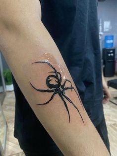 a black and white spider tattoo on the right arm, it looks like he is holding something in his hand