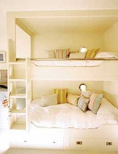 there is a bunk bed in the room with pillows on it and two shelves above