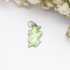 a green pendant sitting on top of a white table next to some flowers and buds