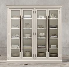 a white bookcase with glass doors and shelves filled with books on top of it