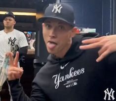 two baseball players standing in the dugout with their arms around each other and pointing