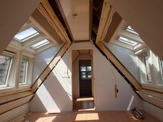 an empty room with skylights and wood flooring on the walls, in front of a doorway