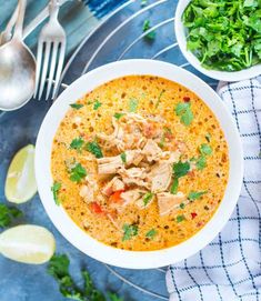 a bowl of soup with chicken and cilantro on the side