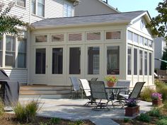 a patio with chairs and tables in front of a house