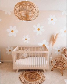 a baby's room with a white crib and flowers on the wall behind it