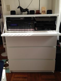 a white dresser with two stereos on top of it and a dog statue in the background