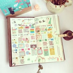 an open book sitting on top of a table next to a cup and keychain