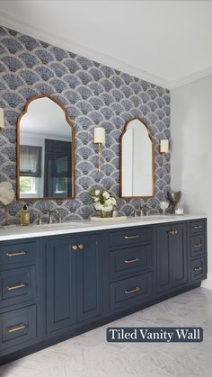 a bathroom with two mirrors and blue cabinets