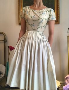 "Gorgeous pale cream cotton dress by Jeanne D'arc. Fitted bodice covered in fabulous embroidery of butterflies on the vine. With capped sleeves, nipped waist, back zipper and a full pleated skirt. Bust: 31-32\" Waist: 23\" Hips: Free Length: 40\" Condition: Excellent vintage condition. There are only two tiny marks on the front of the top, see picture." Summer Dress With Fitted Bodice And Cap Sleeves, Beige Fitted Waist Dress For Spring, White Cotton Dress With Pleated Bodice, White Floral Embroidered Full Skirt Dress, Spring Cotton Dress With Pleated Bodice, Spring White Dress With Pleated Waist, Cotton Short Sleeve Dress With Pleated Waist, Beige Short Sleeve Dress For Garden Party, White Cap Sleeve Summer Dress