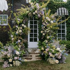 a house covered in vines and flowers next to a white door