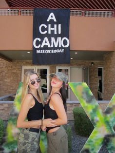 two women standing in front of a building with the letters x and chi camo