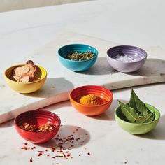 four bowls filled with different types of spices on a counter top next to a cutting board