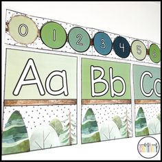 an alphabet poster is hanging on the wall in front of a white background with green and blue letters