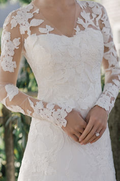 a woman wearing a wedding dress with long sleeves