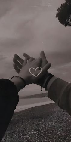 two hands reaching out towards each other with a heart drawn on their palm and the sky in the background