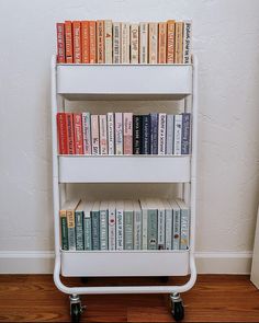 there is a book shelf with many books on it in front of a white wall