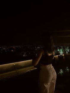 a woman standing on top of a roof at night