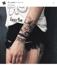 a woman's arm with a flower tattoo on her left wrist and black lace