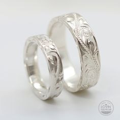 two wedding bands made out of silver with engraved designs on the inside and outside of them