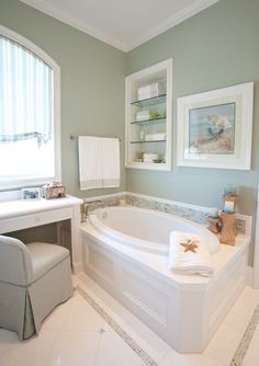 a white bath tub sitting next to a window in a bathroom on top of a tiled floor