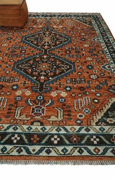 an orange rug with blue and brown designs on the bottom is sitting in front of a chair