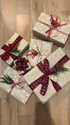 four wrapped presents with red and black bows on them sitting on the floor next to each other