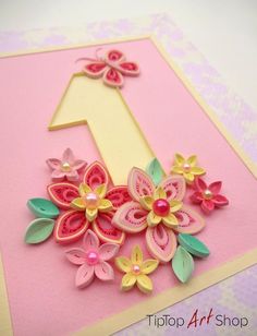 a pink and yellow birthday card with flowers on the number one, made out of paper