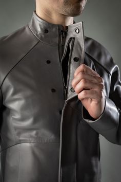 A leather jacket like a concrete slab. The District is inspired by the simple but refined beauty of Brutalist architecture. Clean, stark lines form the body panels and collar, while a hemispherical articulated raglan sleeve provides mobility in a close silhouette. Two front pockets are sealed with magnets, while two large zippered internal pockets offer larger, secure storage. A zippered chest pocket is accessible while the jacket remains zipped shut to provide accessible, discrete, and secure s Modern Fitted Leather Biker Jacket, Modern Leather Jacket For Work, Modern Business Outerwear, Modern Leather Jacket For Business, Modern Fitted Outerwear With Stand Collar, Boris Bidjan Saberi, Leather Outerwear, Scarf Shirt, Brutalist Architecture