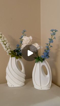 two white vases with blue and white flowers in them