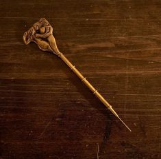 an old wooden stick with a dried flower on it sitting on a wood table top