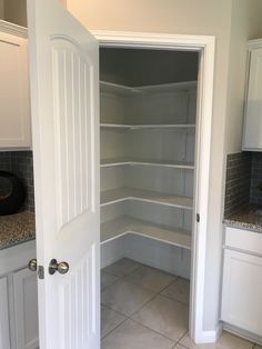 an empty pantry with white cabinets and marble counter tops