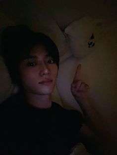 a young man laying in bed with his finger up