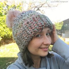 a woman wearing a knitted hat with pom - poms on top of her head