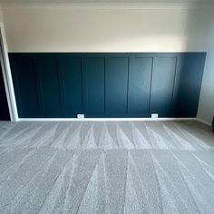 an empty room with blue paneled walls and carpet