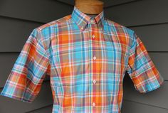 "Gitman Bros. / Est. 1978 100% Cotton Medium, labeled 'M' (please rely on measurements) 2000's or newer 'New Old Stock' Button Down collar short sleeve shirt by one of America's BEST shirtmakers...Gitman Bros.  Bold plaid in Orange and Turquoise with White, Blue, Pink, and Yellow secondary accents. Woven, not a print. High quality cotton poplin. White stitching throughout. Pearl buttons that are hand applied. Made in USA. They don't get much nicer when it comes to traditional short sleeve shirts! Typical starting retail on Gitman short sleeve shirts is $150+. 3 1/4\" button down collar. Eight (8) button fastening on a placket front. Single, pattern matched breast pocket. 1\" hemmed sleeves. Prominent box pleat center below yoke. Tailed bottom hem. One (1) extra button attached, large. 22.5 Classic Plaid Short Sleeve Shirt For Summer, Preppy Plaid Short Sleeve Shirt, Fitted Gingham Shirt With Short Sleeves, Preppy Short Sleeve Summer Shirt, Mens Dress Shirts, Orange And Turquoise, Mens Dress, Pearl Buttons, Button Down Collar