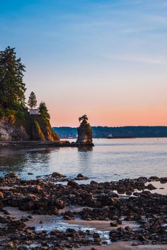 an island in the middle of water with trees on it and rocks at the edge