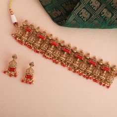 Description : Introducing our striking silver choker set, a standout piece from the Mandira collection, featuring Goddess Lakshmi motif nestled within a temple-inspired design. Enhanced with semi-precious coral stones and clusters of lustrous pearls, this meticulously handcrafted choker set adds a touch of elegance to wedding festivities, soirées, or any memorable occasion. Product Information : Materials used : 925 Silver with Antique Gold Plating Length: Choker-18cm, Earrings-4cm Findings: Hoo Festive Temple Jewelry Choker Necklace, Temple Jewelry Choker Set For Diwali, Red Intricate Design Temple Necklace For Festive Occasions, Diwali Temple Jewelry Choker Set, Festive Temple Jewelry Choker For Puja, Red Spiritual Jewelry For Navratri, Festive Choker Sets For Festivals, Silver Temple Jewelry Sets For Ceremonial Occasion, Diwali Festive Temple Choker Necklace